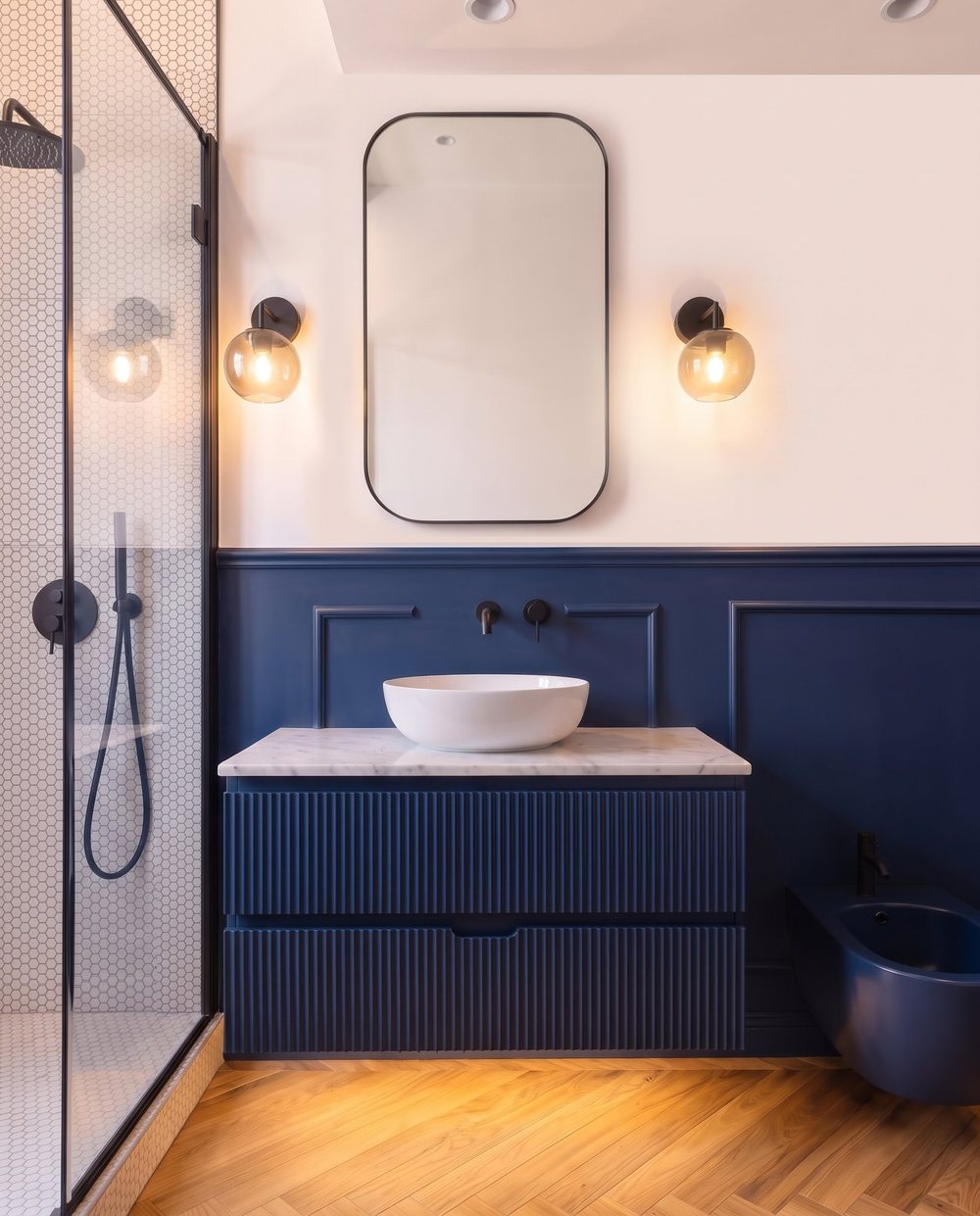 Integrazione tra zona doccia e mobile su misura nel bagno blu.